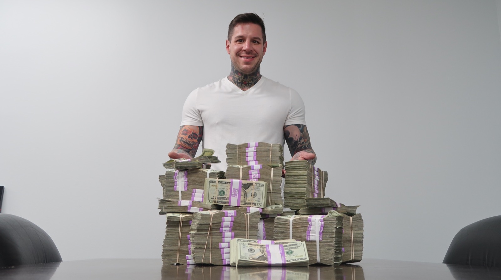 Archival photograph of Justin Gilmore standing behind stacks of banded cash on a conference table